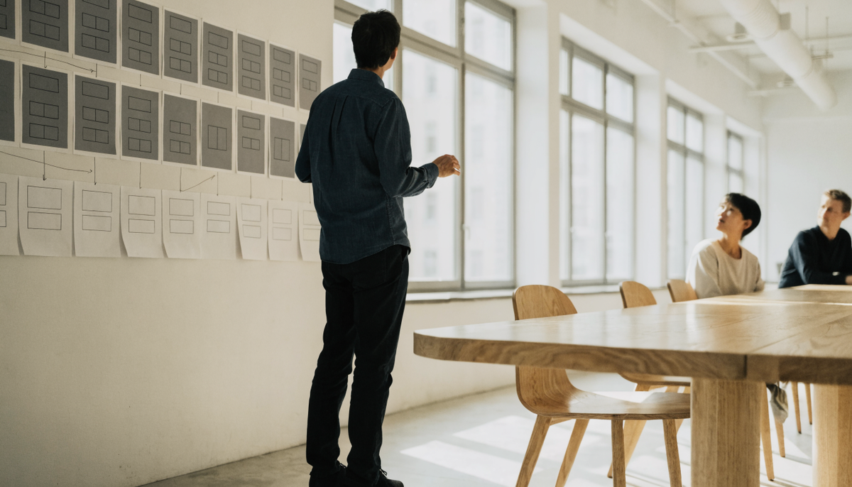 Berater erklärt an einer Wand mit Wireframes die alte und die neue Website-Struktur vor dem Relaunch